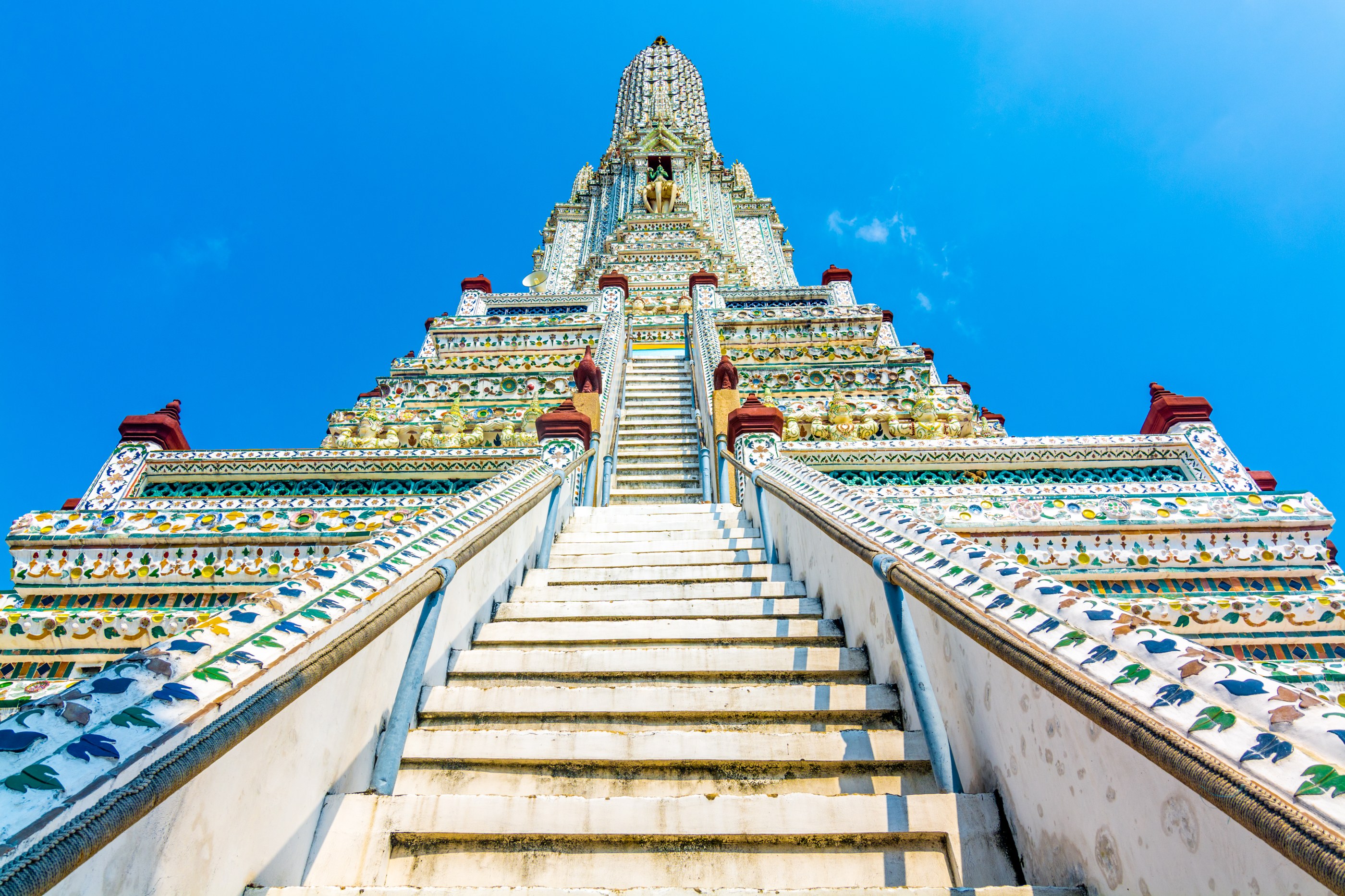 La torre bianca e i mosaici colorati di Wat Arun a Bangkok contro il cielo azzurro