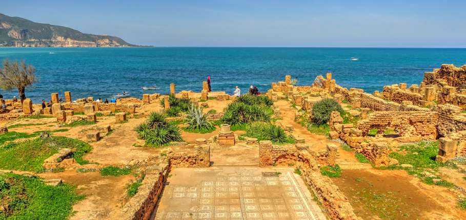 Le rovine di Tipaza tra palme, pietra dorata e il mare azzurro del Mediterraneo