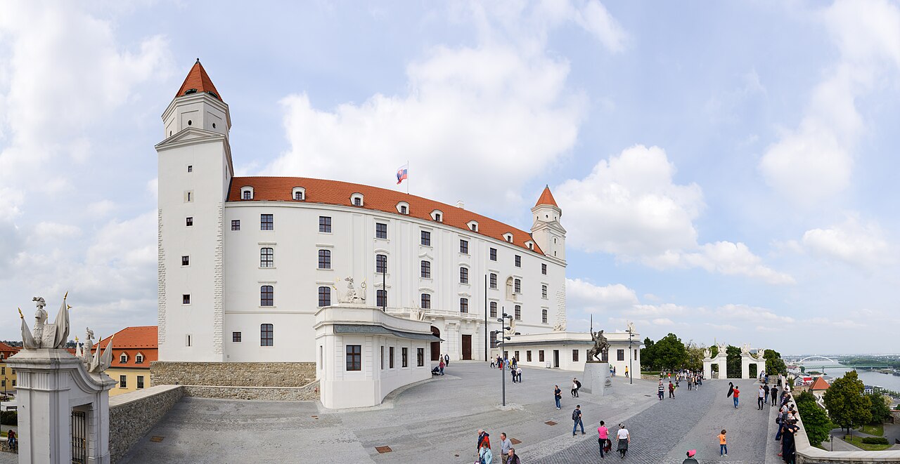 Il castello bianco di Bratislava sotto il cielo luminoso, con il Danubio sullo sfondo.