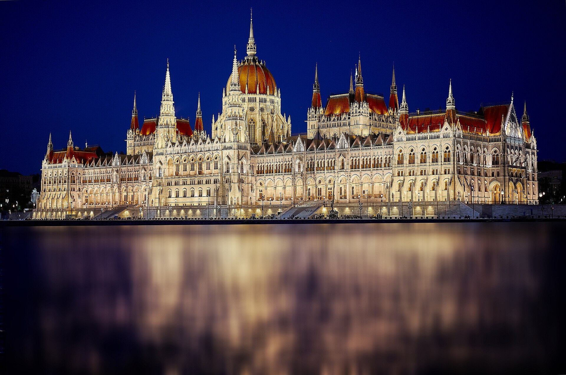 Il Parlamento ungherese illuminato si riflette nel Danubio all’ora blu, a Budapest.