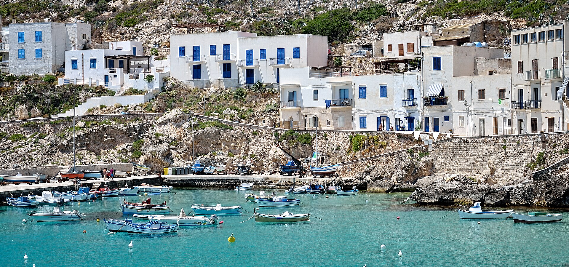 Case bianche con persiane blu e barche nel porticciolo di Levanzo