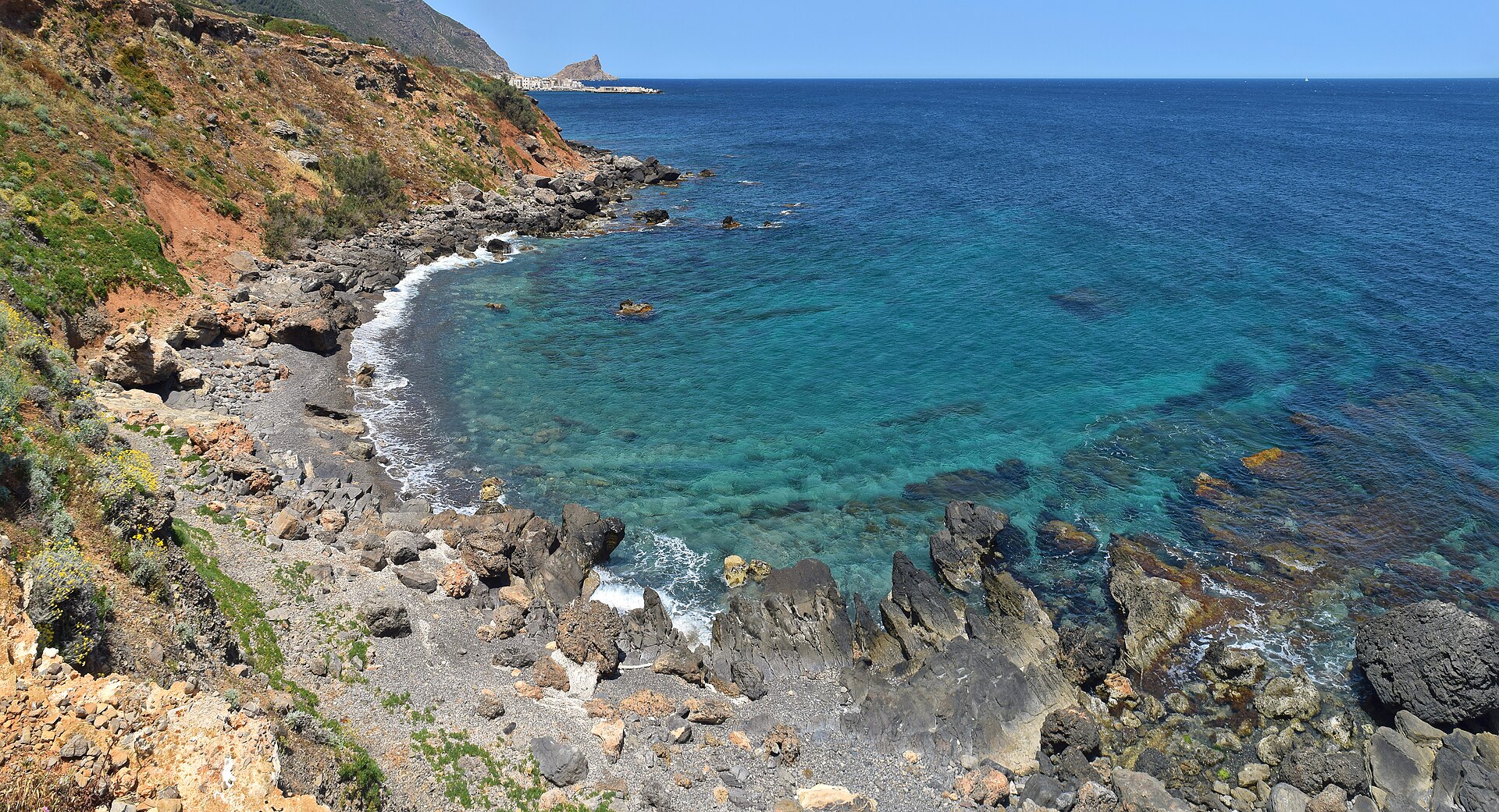Costa rocciosa di Marettimo con mare trasparente e il borgo sullo sfondo