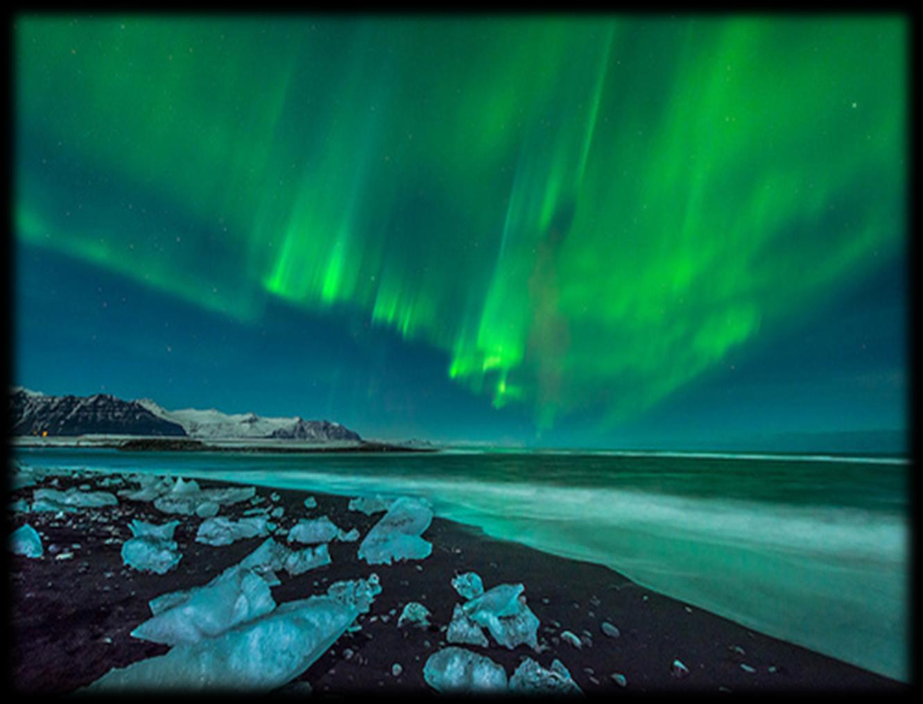 Grüne Nordlichter über einem isländischen Strand mit Eisblöcken