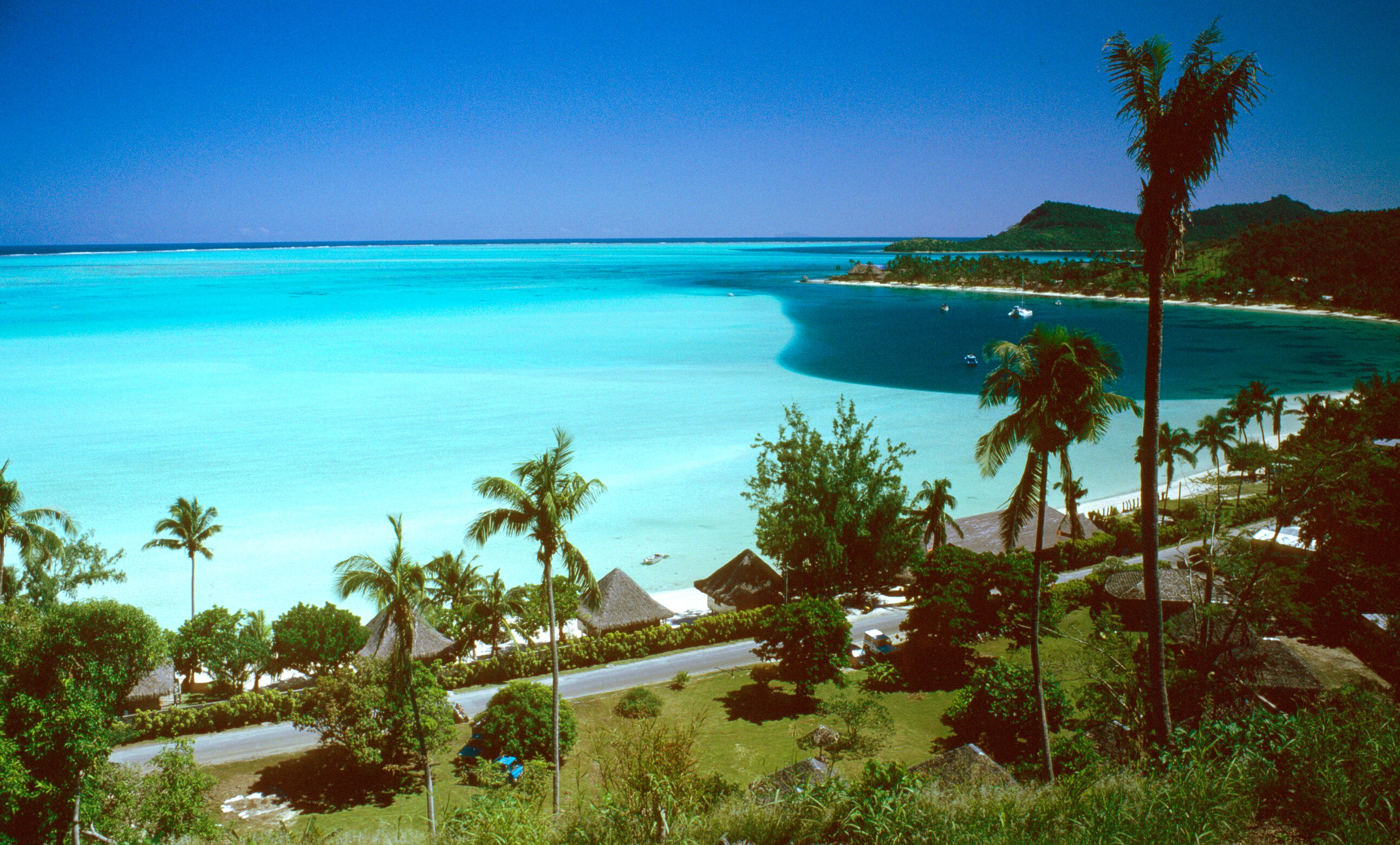 Le acque turchesi di Matira a Bora Bora, con palme e spiaggia